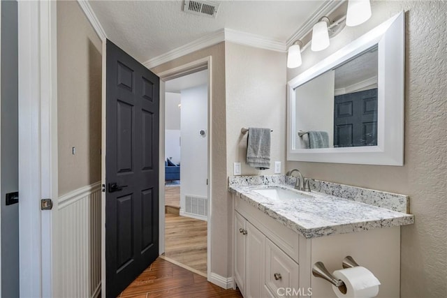 2578 Bryce Ct, Colton, CA 92324 - bathroom featuring wood finished floors, vanity, ornamental molding, and a textured wall