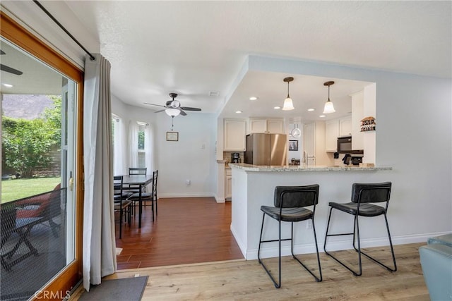 2578 Bryce Ct, Colton, CA 92324 - kitchen featuring freestanding refrigerator, white cabinetry, light wood-style flooring, a peninsula, and recessed lighting