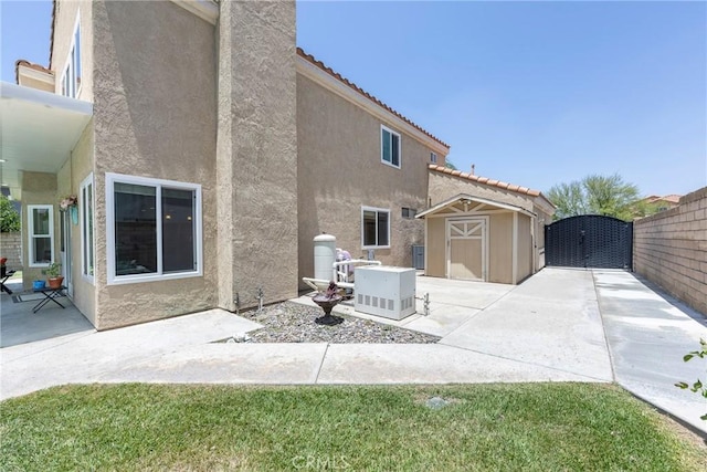 2578 Bryce Ct, Colton, CA 92324 - rear view of house with a storage shed, stucco siding, a patio area, a tiled roof, and a gate