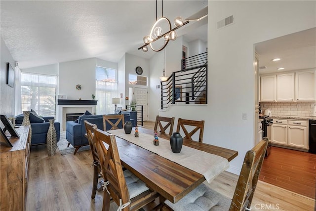2578 Bryce Ct, Colton, CA 92324 - dining area featuring light wood-style flooring, stairs, a fireplace, high vaulted ceiling, and a chandelier
