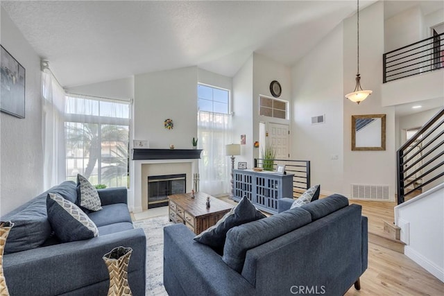 2578 Bryce Ct, Colton, CA 92324 - living area featuring high vaulted ceiling, light wood-style flooring, a glass covered fireplace, and stairs
