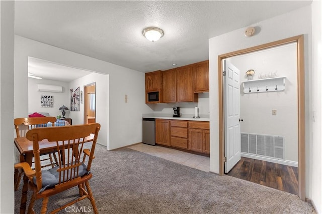44125 Dusty Rd, Lancaster, CA 93536 - kitchen featuring light colored carpet, dishwasher, brown cabinets, an AC wall unit, and black microwave