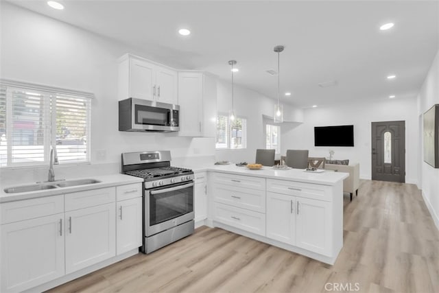 2697 Merced St, Los Angeles, CA 90065 - kitchen featuring appliances with stainless steel finishes, a peninsula, white cabinets, light countertops, and light wood finished floors