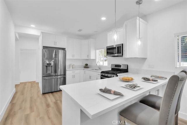 2697 Merced St, Los Angeles, CA 90065 - kitchen with appliances with stainless steel finishes, a peninsula, light countertops, white cabinetry, and light wood-style floors