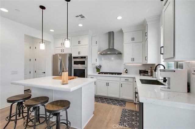 783 Longhorn, Rancho Mission Viejo, CA 92694 - kitchen featuring wall chimney range hood, appliances with stainless steel finishes, a kitchen island, light wood-style floors, and white cabinetry