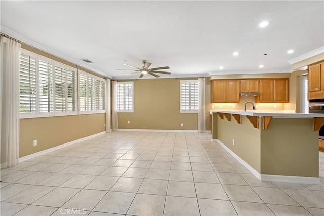 11529 Trailrun Ct, Riverside, CA 92505 - kitchen with ornamental molding, a ceiling fan, light countertops, a breakfast bar, and under cabinet range hood