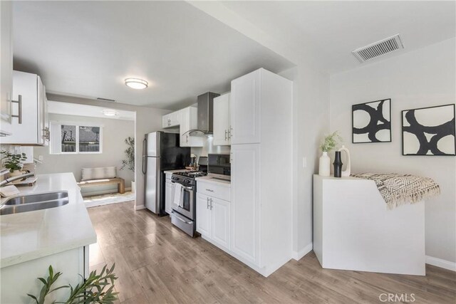 21237 Silver Cloud Dr, Diamond Bar, CA 91765 - kitchen featuring appliances with stainless steel finishes, wall chimney range hood, light countertops, and light wood-style floors