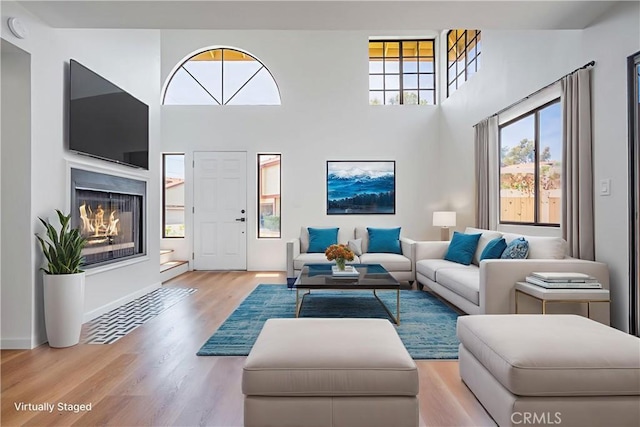 8939 Gallatin Rd Unit 68, Pico Rivera, CA 90660 - living area featuring wood finished floors, a glass covered fireplace, and a high ceiling