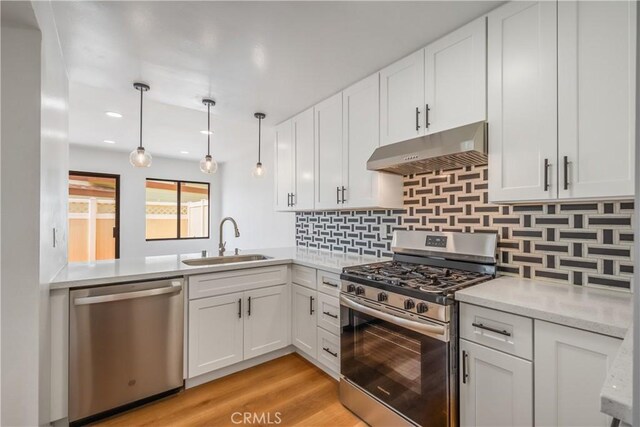 8939 Gallatin Rd Unit 68, Pico Rivera, CA 90660 - kitchen with appliances with stainless steel finishes, under cabinet range hood, white cabinets, decorative backsplash, and light wood-style floors