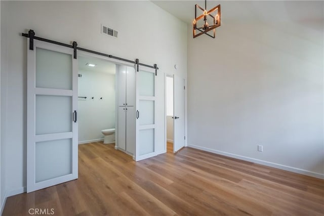 8939 Gallatin Rd Unit 68, Pico Rivera, CA 90660 - unfurnished bedroom with a barn door, a chandelier, a towering ceiling, wood finished floors, and ensuite bath