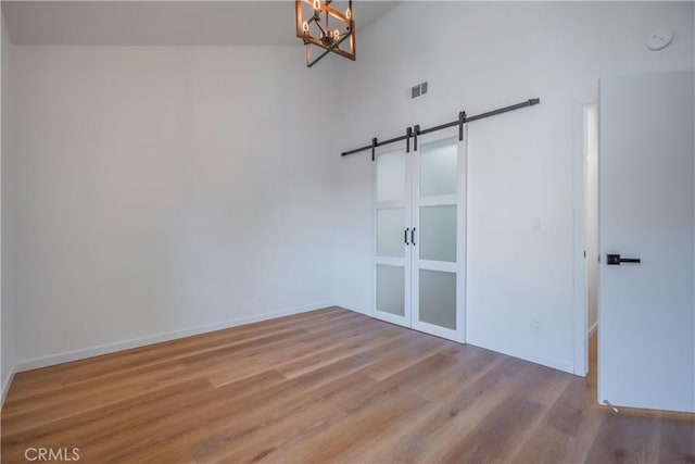 8939 Gallatin Rd Unit 68, Pico Rivera, CA 90660 - spare room featuring a barn door, wood finished floors, and a chandelier