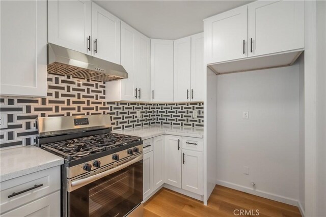 8939 Gallatin Rd Unit 68, Pico Rivera, CA 90660 - kitchen with gas stove, under cabinet range hood, light wood finished floors, white cabinets, and decorative backsplash