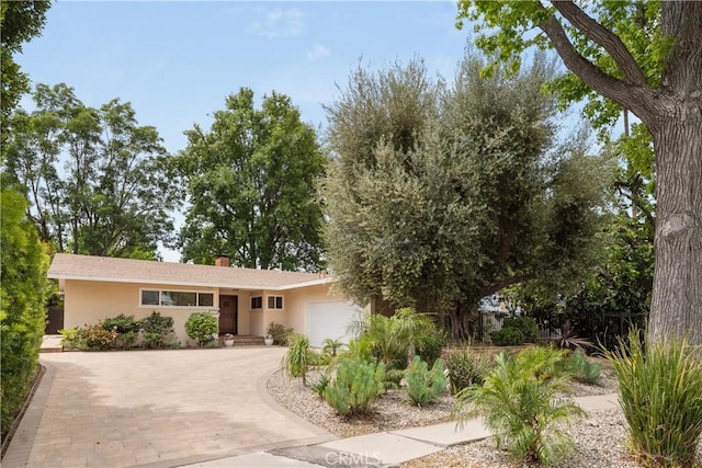 15936 Osborne St, North Hills, CA 91343 - view of front facade with a garage, decorative driveway, stucco siding, and a chimney