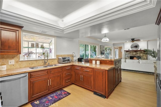 22550 Flamingo St, Woodland Hills, CA 91364 - kitchen featuring stainless steel dishwasher, light wood-style floors, a tiled fireplace, a peninsula, and tasteful backsplash