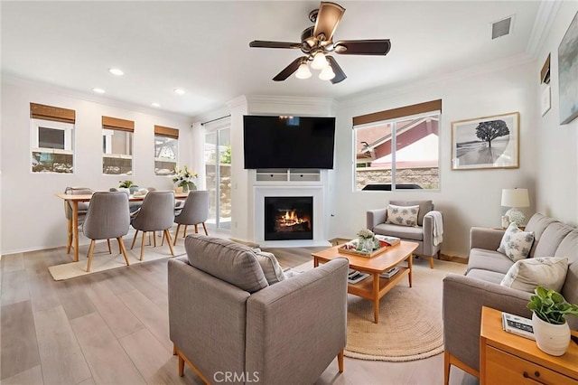 72 Westwind Dr, Tustin, CA 92782 - living room featuring healthy amount of natural light, crown molding, ceiling fan, light wood finished floors, and a warm lit fireplace