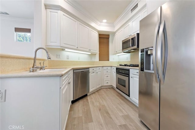 72 Westwind Dr, Tustin, CA 92782 - kitchen featuring stainless steel appliances, ornamental molding, white cabinets, light wood-type flooring, and light countertops