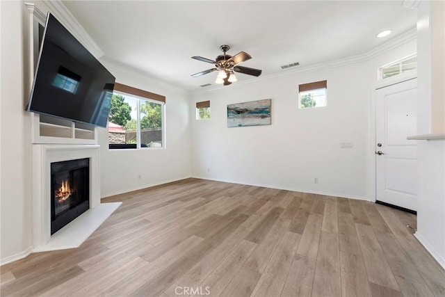 72 Westwind Dr, Tustin, CA 92782 - unfurnished living room featuring plenty of natural light, light wood finished floors, ceiling fan, a glass covered fireplace, and ornamental molding