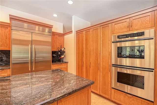 4570 Christine Loomis Dr, Arroyo Grande, CA 93420 - kitchen featuring stainless steel appliances, dark stone countertops, recessed lighting, light tile patterned floors, and brown cabinetry