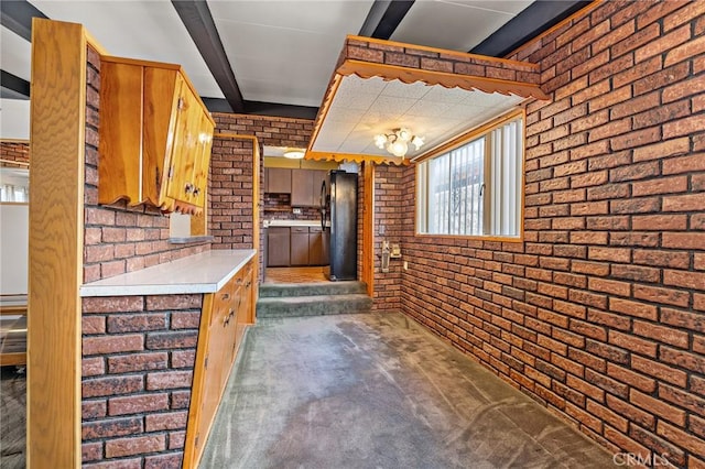 9649 Grace St, Fontana, CA 92335 - kitchen featuring brick wall, freestanding refrigerator, light countertops, brown cabinets, and beam ceiling