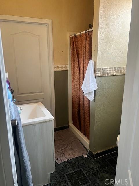 1550 W 21st St, San Bernardino, CA 92411 - full bath featuring curtained shower and a wainscoted wall