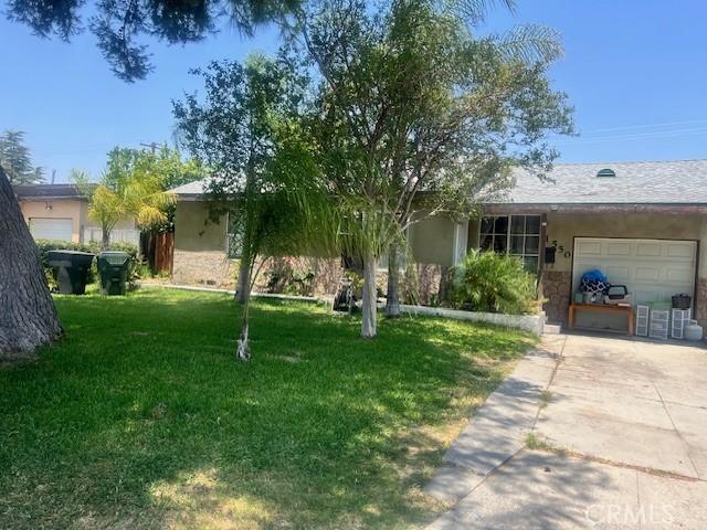 1550 W 21st St, San Bernardino, CA 92411 - view of front facade featuring a garage, concrete driveway, a front yard, stucco siding, and stone siding