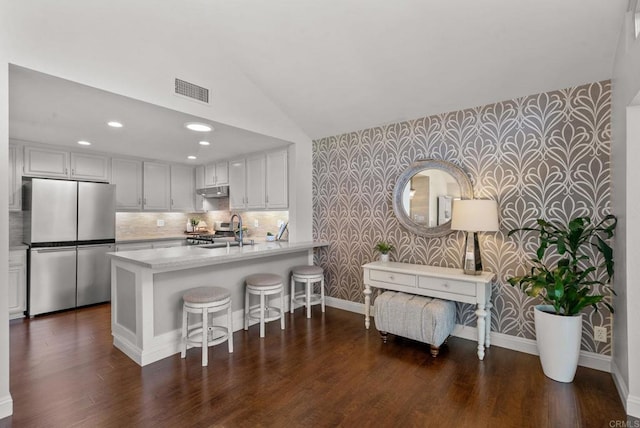 1247 La Casa Dr, San Marcos, CA 92078 - kitchen featuring wallpapered walls, appliances with stainless steel finishes, an accent wall, light countertops, and vaulted ceiling