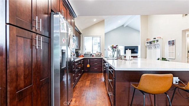 937 Dahlia Ave, Costa Mesa, CA 92626 - kitchen with stainless steel fridge with ice dispenser, vaulted ceiling, dark wood-style floors, light countertops, and a breakfast bar area