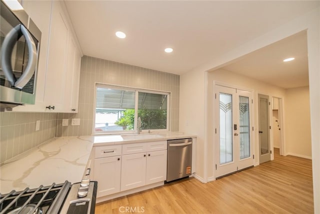2648 Condor Cir, Corona, CA 92882 - kitchen with appliances with stainless steel finishes, light wood finished floors, backsplash, white cabinets, and light stone counters