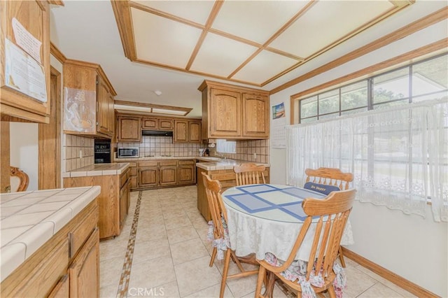 2837 E Mesa Dr, West Covina, CA 91791 - kitchen with tile countertops, light tile patterned floors, tasteful backsplash, brown cabinetry, and stainless steel microwave