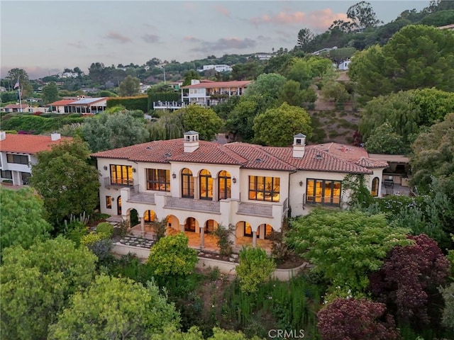 6337 Via Colinita, Rancho Palos Verdes, CA 90275 - back of property at dusk featuring a chimney, stucco siding, a tiled roof, a balcony, and view of scattered trees