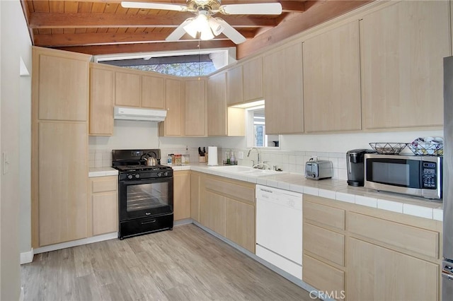 10632 Larry Dr, Anaheim, CA 92804 - kitchen featuring dishwasher, black gas stove, light brown cabinetry, under cabinet range hood, and stainless steel microwave