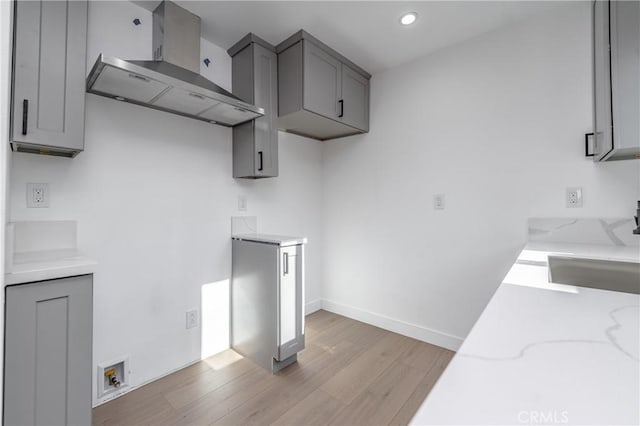 3818 Crawford St, Los Angeles, CA 90011 - kitchen with wall chimney exhaust hood, light wood-style flooring, light stone counters, gray cabinets, and recessed lighting