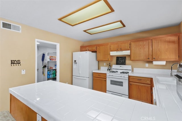 23050 Catt Rd, Wildomar, CA 92595 - kitchen with white appliances, under cabinet range hood, tile counters, a peninsula, and brown cabinets