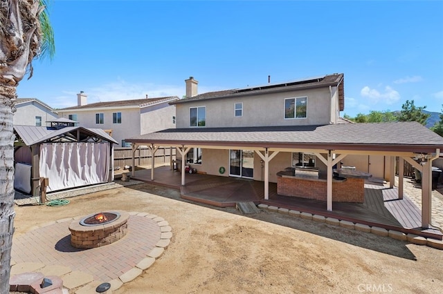 23050 Catt Rd, Wildomar, CA 92595 - back of house featuring an outdoor fire pit, roof mounted solar panels, stucco siding, a shed, and a deck