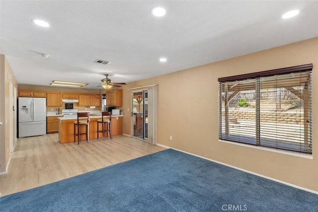23050 Catt Rd, Wildomar, CA 92595 - kitchen with white fridge with ice dispenser, light countertops, brown cabinets, range, and a breakfast bar area