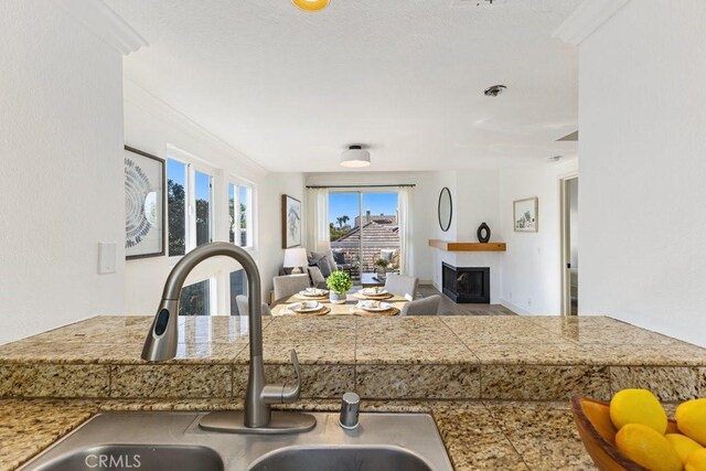 20371 Bluffside Cir Unit B401, Huntington Beach, CA 92646 - kitchen featuring tile counters, open floor plan, a fireplace, and ornamental molding