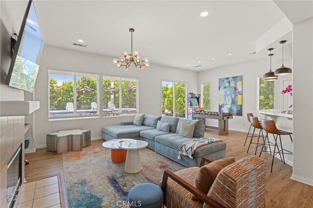 80848 Sunspring Ct, Indio, CA 92201 - living room featuring healthy amount of natural light, a tiled fireplace, a chandelier, light wood-style flooring, and recessed lighting