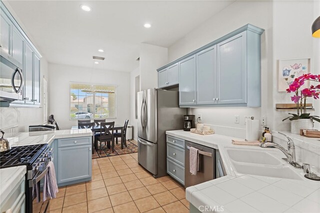 80848 Sunspring Ct, Indio, CA 92201 - kitchen featuring appliances with stainless steel finishes, tile countertops, light tile patterned flooring, recessed lighting, and hanging light fixtures