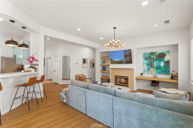 80848 Sunspring Ct, Indio, CA 92201 - living room featuring light wood-style flooring, built in features, recessed lighting, a tiled fireplace, and a chandelier