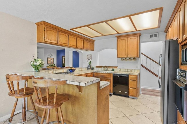 5855 Kappa St, La Mesa, CA 91942 - kitchen with stainless steel appliances, a peninsula, a breakfast bar area, tile counters, and arched walkways