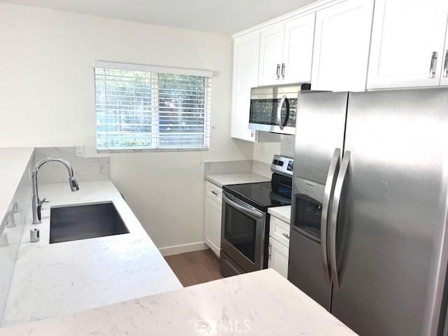 28512 Conejo View Dr, Agoura Hills, CA 91301 - kitchen with stainless steel appliances, light stone countertops, wood finished floors, and white cabinetry
