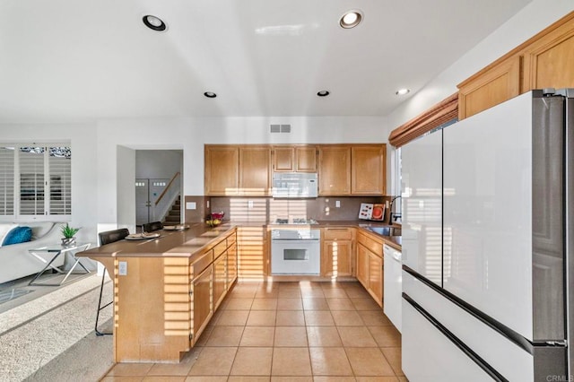 13756 Fontanelle Pl, San Diego, CA 92128 - kitchen with white appliances, a peninsula, tasteful backsplash, recessed lighting, and light tile patterned flooring
