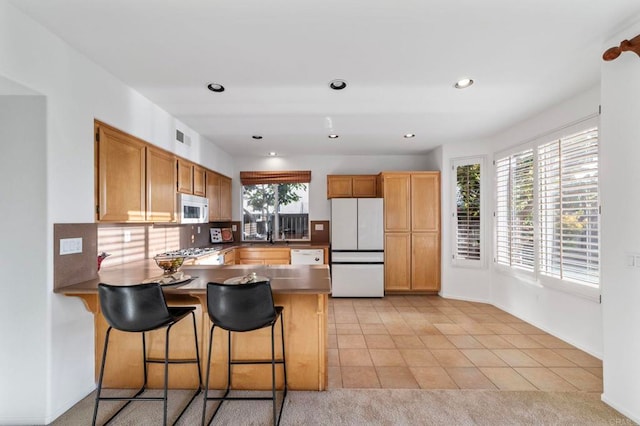 13756 Fontanelle Pl, San Diego, CA 92128 - kitchen featuring white appliances, a peninsula, light tile patterned floors, a breakfast bar area, and recessed lighting