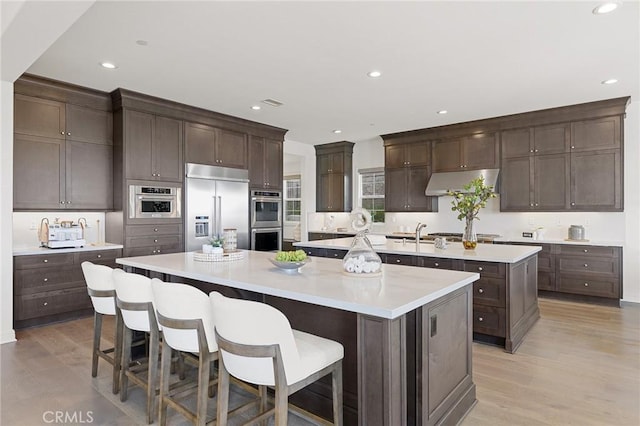 19818 Cornell Ln, Yorba Linda, CA 92886 - kitchen with appliances with stainless steel finishes, a spacious island, range hood, dark brown cabinets, and recessed lighting