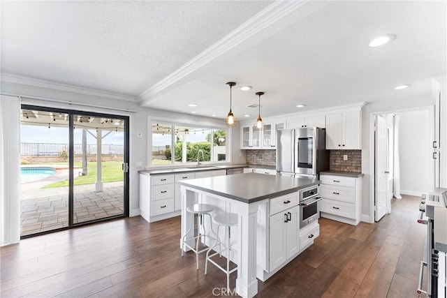 28422 La Pradera, Laguna Niguel, CA 92677 - kitchen with stainless steel appliances, crown molding, a breakfast bar, glass insert cabinets, and white cabinets