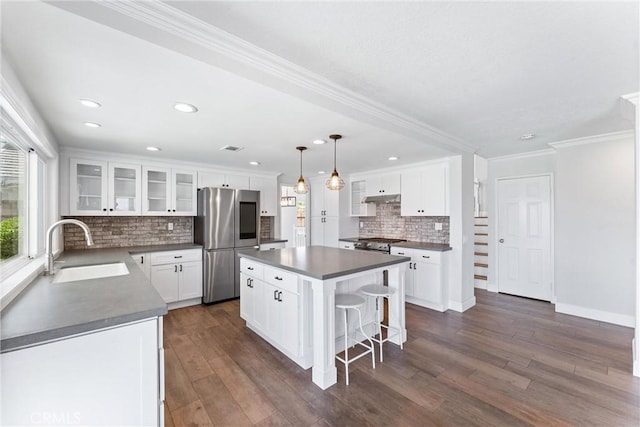 28422 La Pradera, Laguna Niguel, CA 92677 - kitchen with stainless steel appliances, under cabinet range hood, a kitchen island, tasteful backsplash, and dark countertops