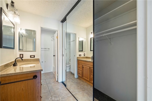 5585 E Pacific Coast Unit 144, Long Beach, CA 90804 - bathroom with two vanities, tile patterned flooring, and a textured ceiling