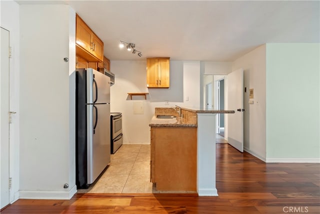 5585 E Pacific Coast Unit 144, Long Beach, CA 90804 - kitchen featuring stainless steel appliances, a peninsula, light wood-style flooring, and stone countertops