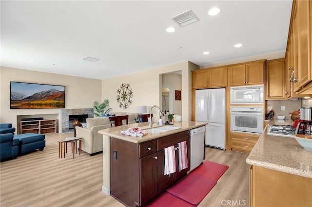 3667 Skylark Way, Brea, CA 92823 - kitchen with white appliances, light wood-style flooring, a kitchen island with sink, light stone counters, and backsplash