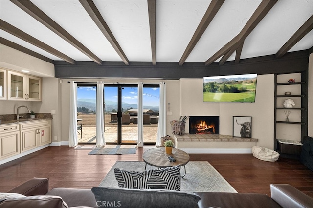 38225 Camino Sierra Rd, Temecula, CA 92592 - living room with a lit fireplace, beam ceiling, and dark wood-style flooring